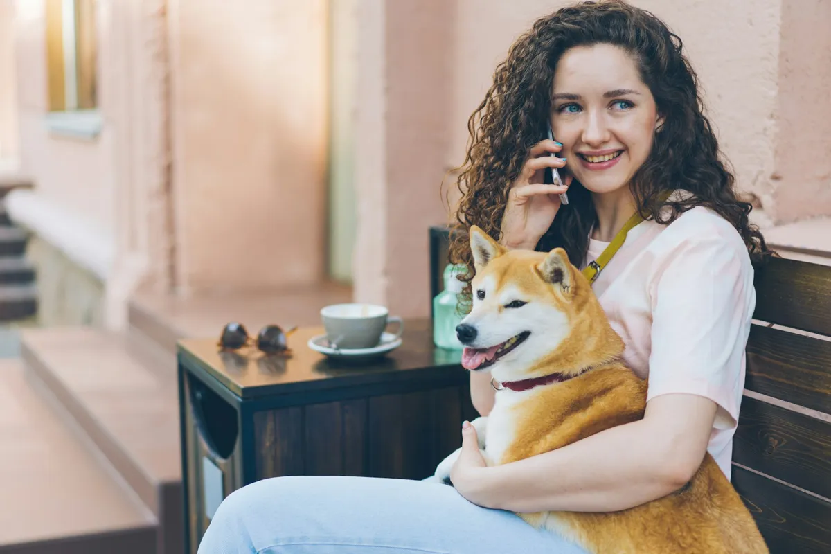 Una mujer habla por teléfono con su perro en el regazo
